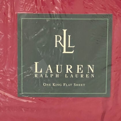 Top-down close-up of the Ralph Lauren Lauren’s Solid barn red king flat sheet in original packaging with the Ralph Lauren placard centered.
