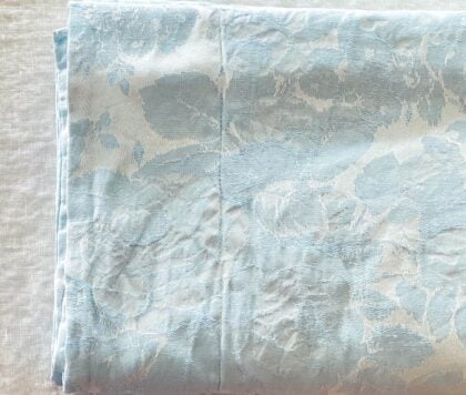 Top-down close-up of Nancy Koltes pale blue embossed flanged sham quarter-folded showing texture and top-stitching.