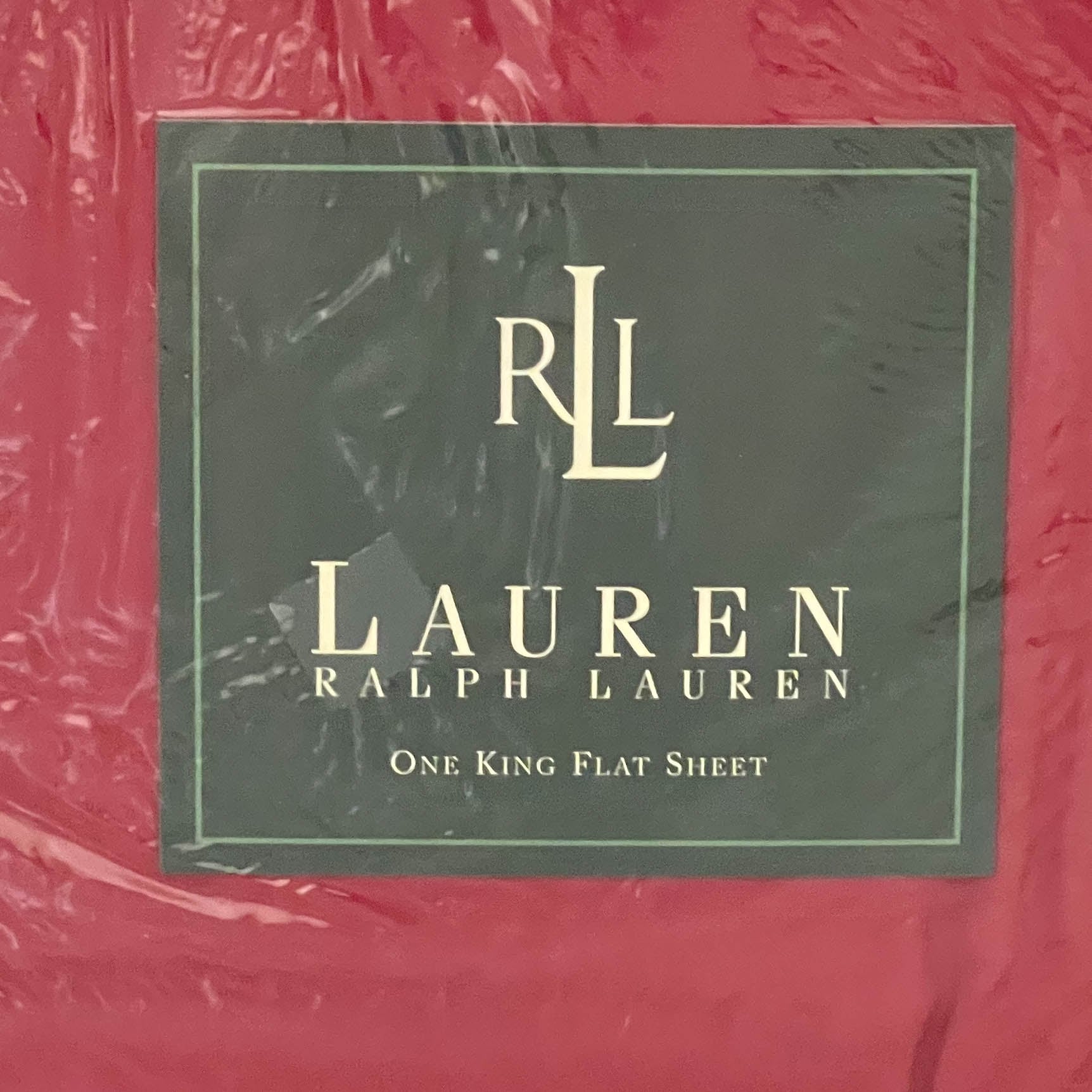 Top-down close-up of the Ralph Lauren Lauren’s Solid barn red king flat sheet in original packaging with the Ralph Lauren placard centered.