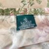 Close-up of Ralph Lauren Adriana Floral tag sewn into the edge of king flat sheet on light taupe background.