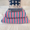 Side view of Ralph Lauren American Summer Stripe King sheet set neatly stacked showing layers of red white and blue striped cotton sheets and pillowcases