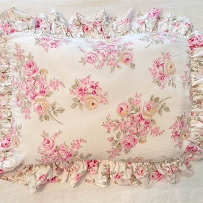 Top-down view of Simply Shabby Chic “Blush Beauty” ruffled sham (28 × 20) showing pink and white peonies, yellow gold touches, pink wildflowers and greenery on off-white 100% cotton background – romantic vintage cottage-style bedding