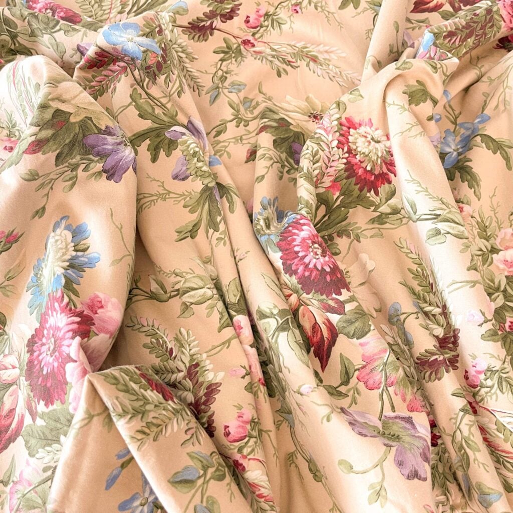 Top-down view of rumpled Ralph Lauren Adriana Floral king flat sheet showing pink peonies and roses on light taupe background.