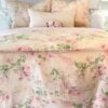 Full bedroom view of the vintage Ralph Lauren Therese bedding set, featuring blush-pink roses and sage green leaves on a cream cotton duvet with matching pillowcases and sheets