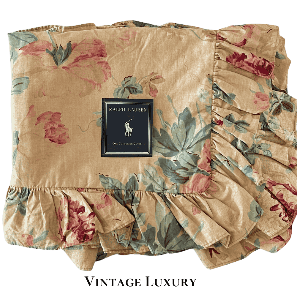 Top-down view of the Ralph Lauren Elsa Grassland ruffled shams folded in quarters with the Ralph Lauren placard placed on top, showing the gold background with pink and red peonies.