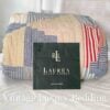 Folded side view of the Ralph Lauren Chadwick Blue King Patchwork Quilt showing soft red, white, light blue, and cream patchwork strips with the Ralph Lauren placard in front