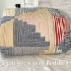 Side shot of the folded and rolled Ralph Lauren Chadwick Blue King Patchwork Quilt highlighting the soft red, white, light blue, and cream patchwork pattern