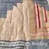 Close-up shot of the Ralph Lauren Chadwick Blue patchwork quilt showing red, white, light blue, and cream fabric strips in a soft Americana design