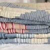 Side shot of the neatly folded Ralph Lauren Chadwick Blue King Patchwork Quilt showing the light red, white, blue, and cream patchwork edges