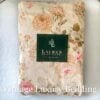 Top-down view of the neatly folded Ralph Lauren Woodstock California king fitted sheet with the Ralph Lauren placard on top.
