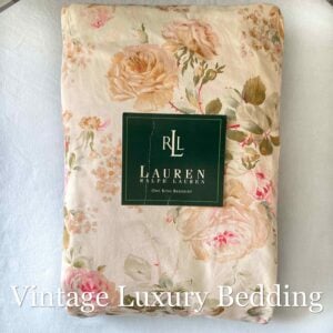 Top-down view of the neatly folded Ralph Lauren Woodstock California king fitted sheet with the Ralph Lauren placard on top.