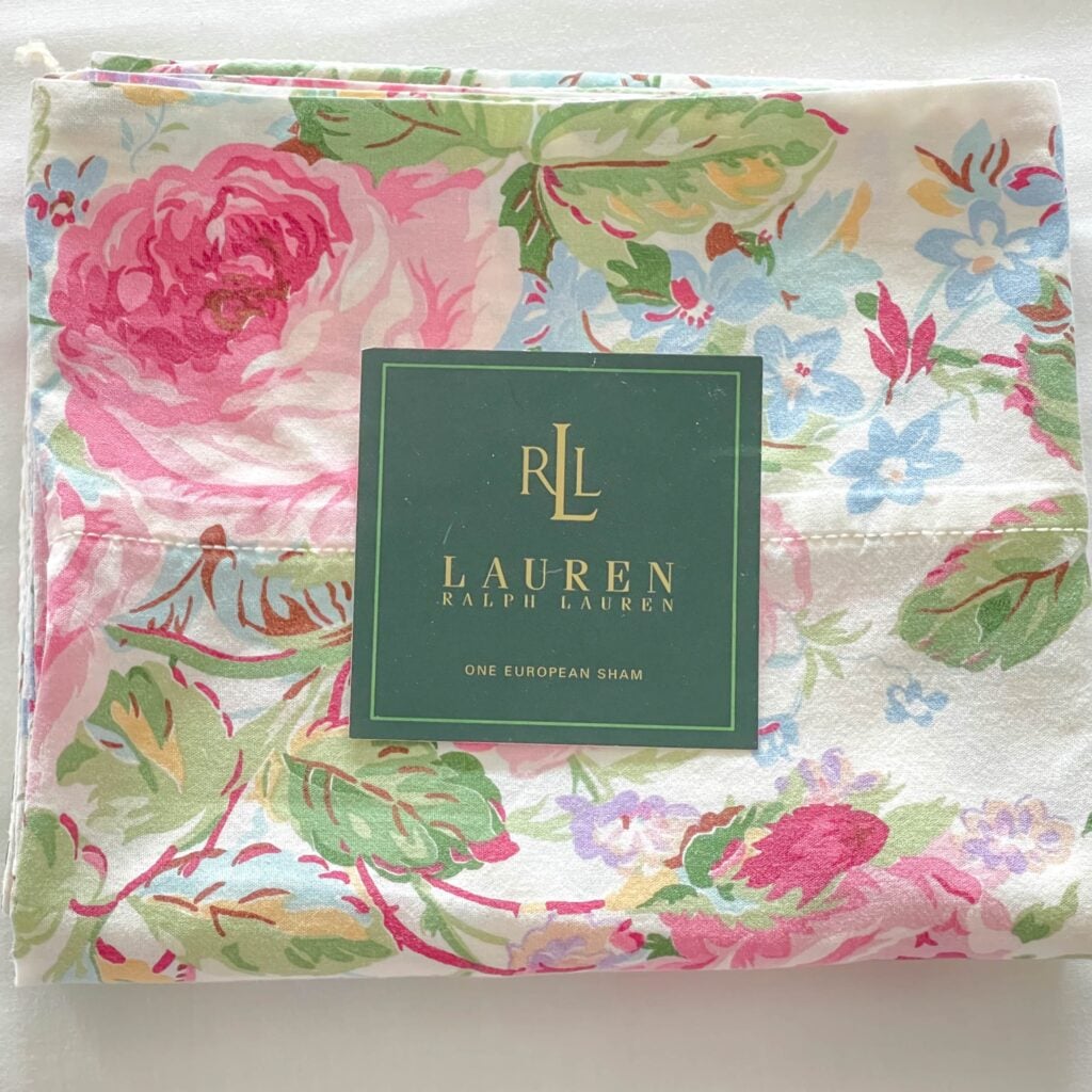 Top-down photo of vintage Ralph Lauren Water Floral Pink pillowcase folded with placard on top