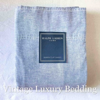 Neatly folded Polo Ralph Lauren denim queen flat sheet with navy Ralph Lauren placard on top