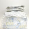 Simply Shabby Chic British Rose king patchwork quilt folded with matching white ruffled pillow shams in soft blue, white, and pale green floral patchwork