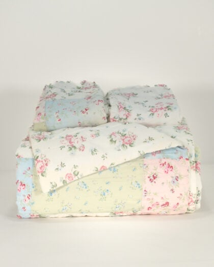 Simply Shabby Chic patchwork top-stitched queen reversible quilt and matching ruffled shams folded and stacked front view