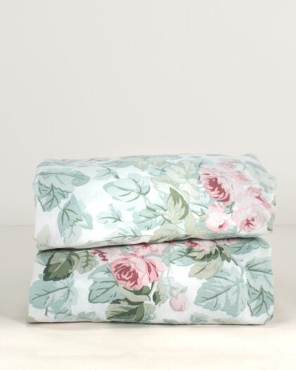 Pair of folded Laura Ashley Cottage Rose ruffled shams with pink roses and sage green foliage