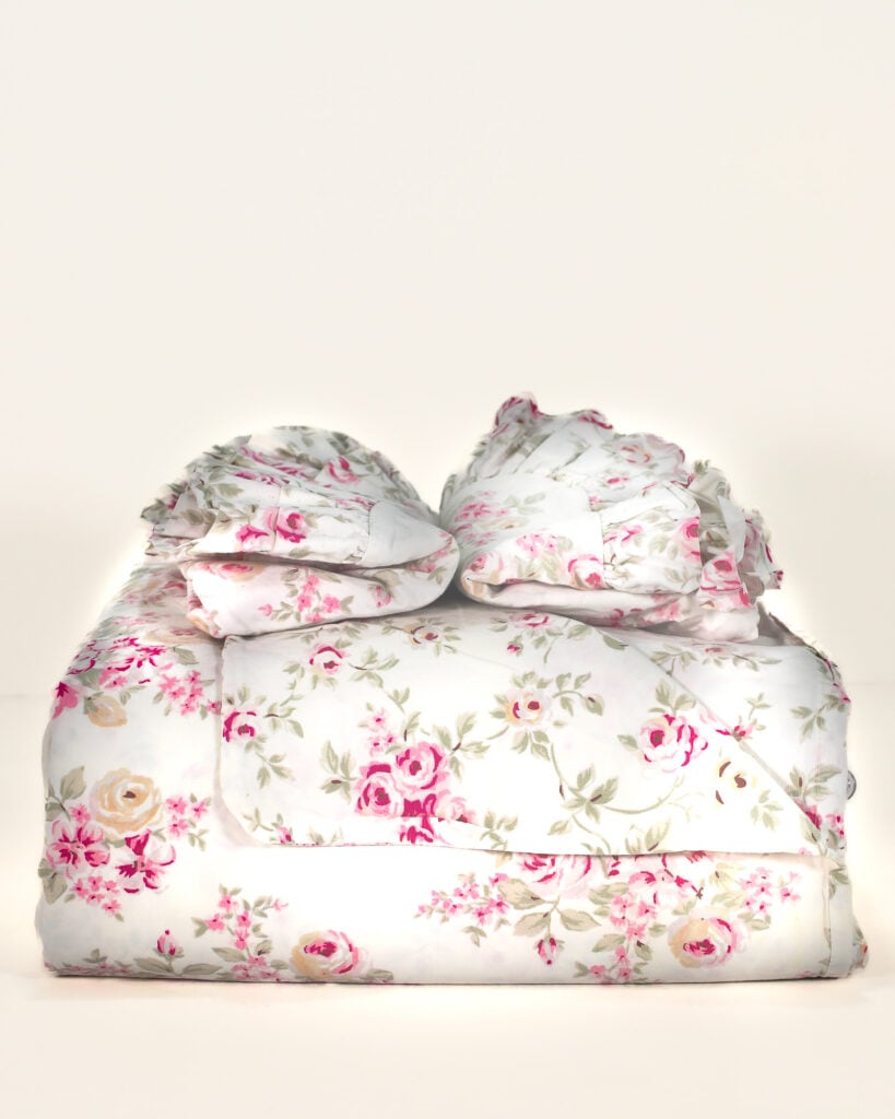 Front view of neatly folded Simply Shabby Chic Blush Beauty queen duvet cover stacked with matching ruffled shams