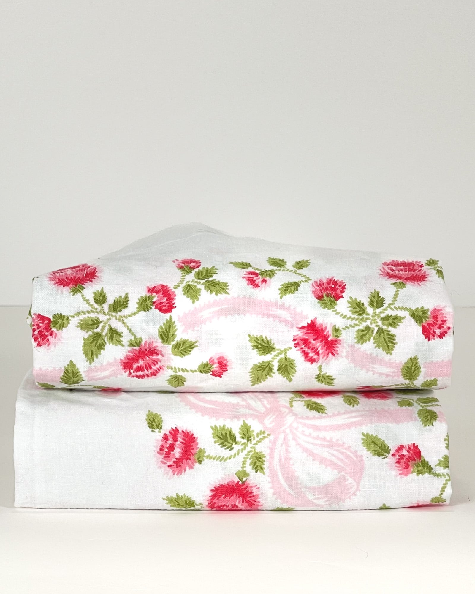 Pair of folded vintage Springmaid Muslin pillowcases with red wildflower print on crisp white cotton