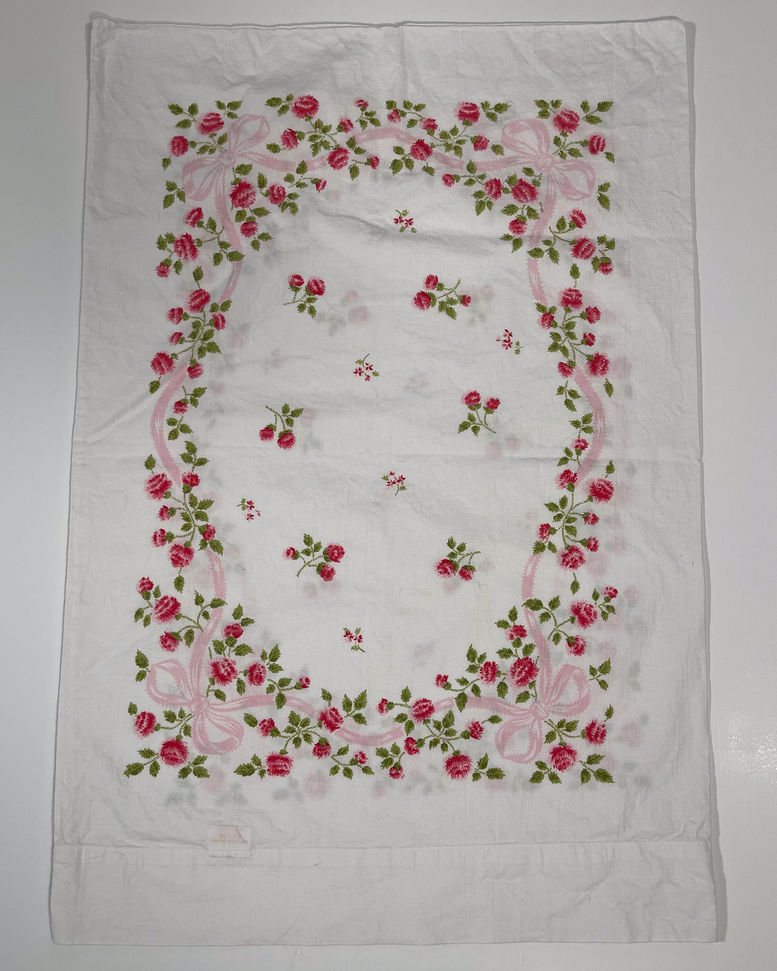 Full top-down view of vintage Springmaid Muslin pillowcase with red wildflowers and pink ribbon detail