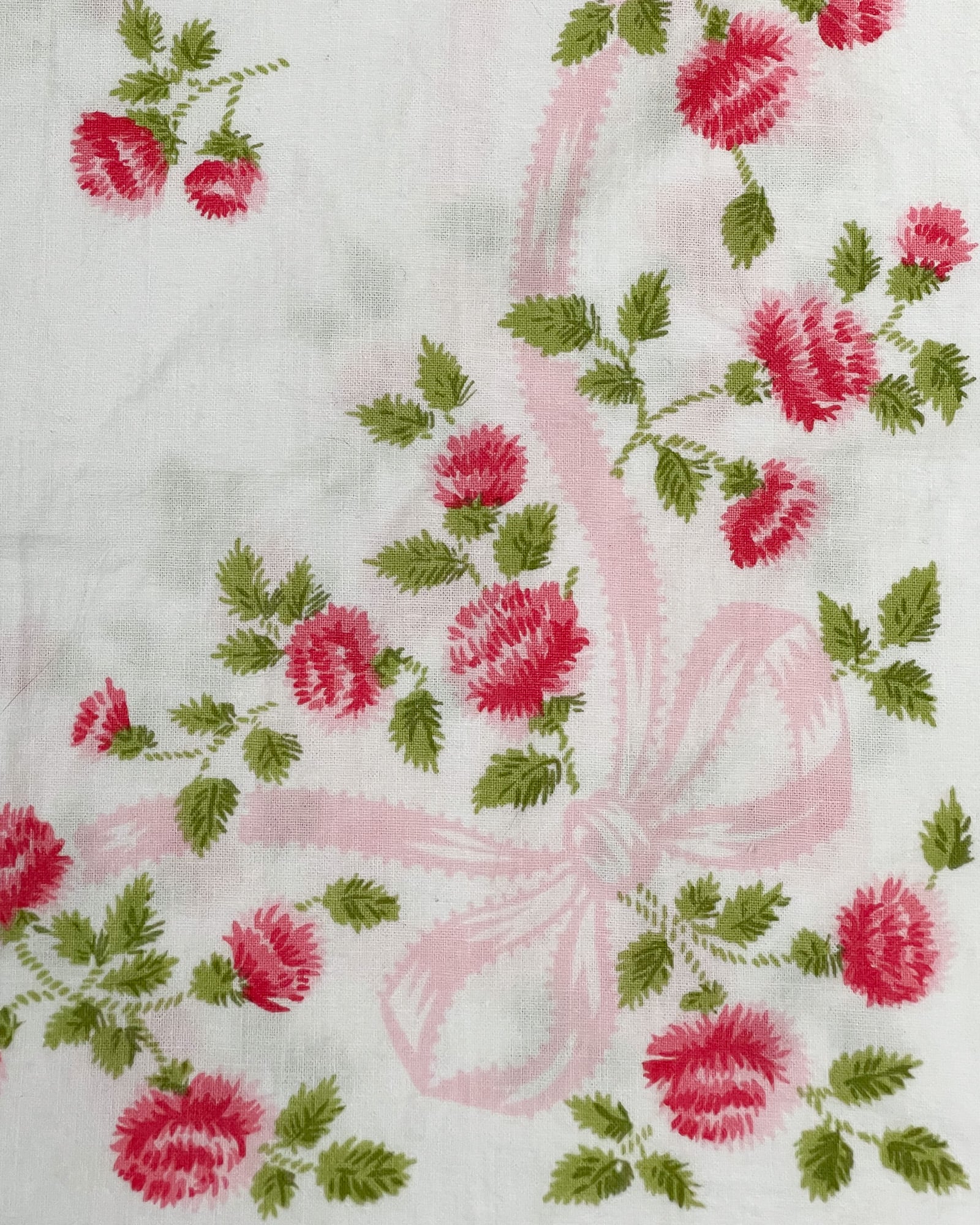 Close-up of corner design on vintage Springmaid Muslin pillowcase with pink ribbon scroll and red wildflowers