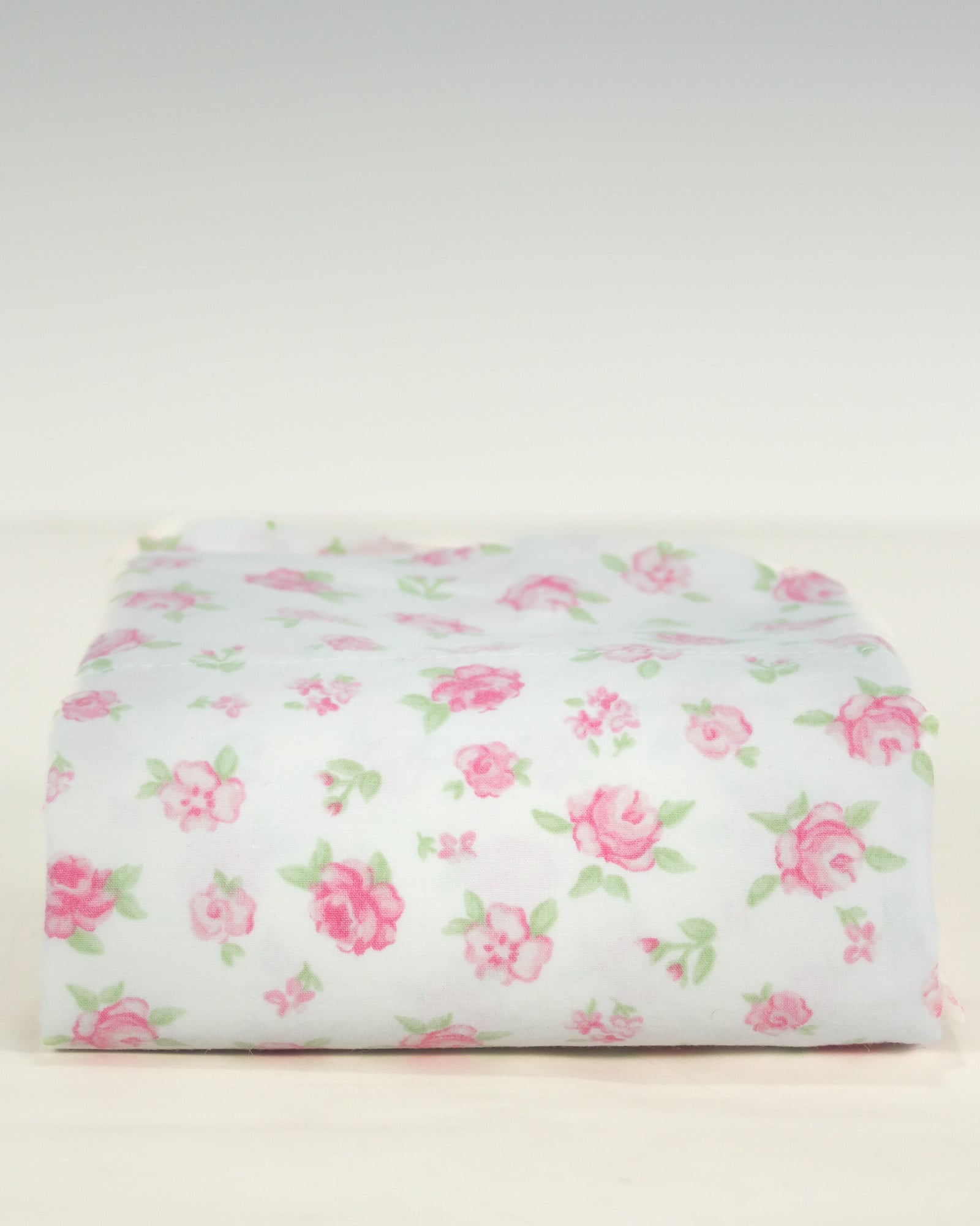 Folded vintage standard pillowcase in white cotton with soft pink ditsy rose floral print