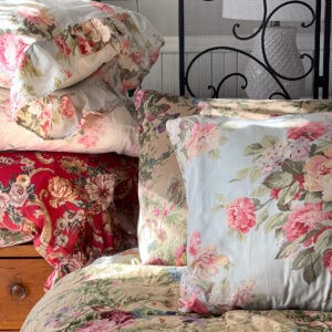 English country bed styled with Ralph Lauren Adriana Blue bedding, Stone Harbor ruffled pillowcase, and floral ruffled pillows beside a wrought iron bed