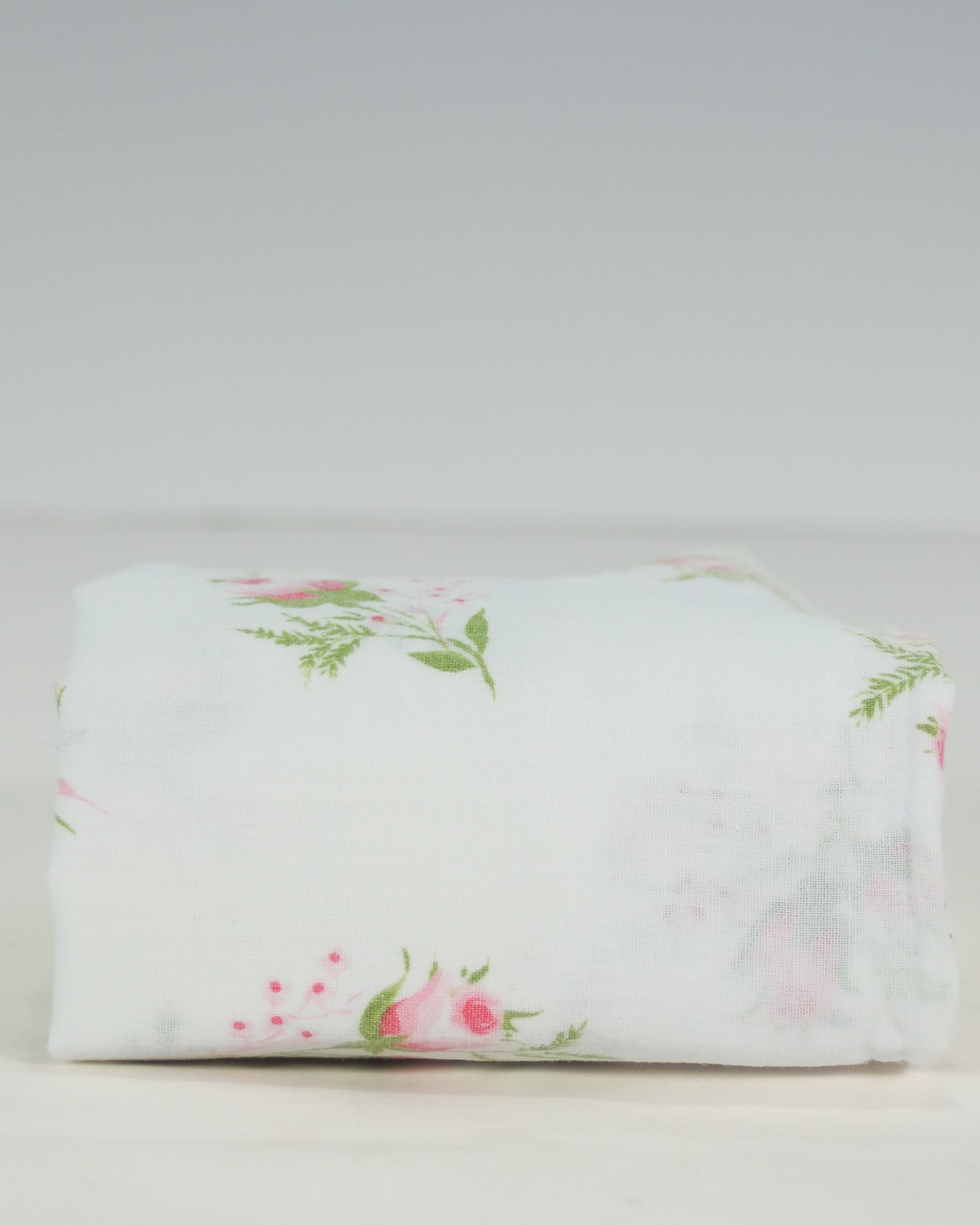 Folded vintage single pillowcase in white cotton with scattered pink rosebud floral print