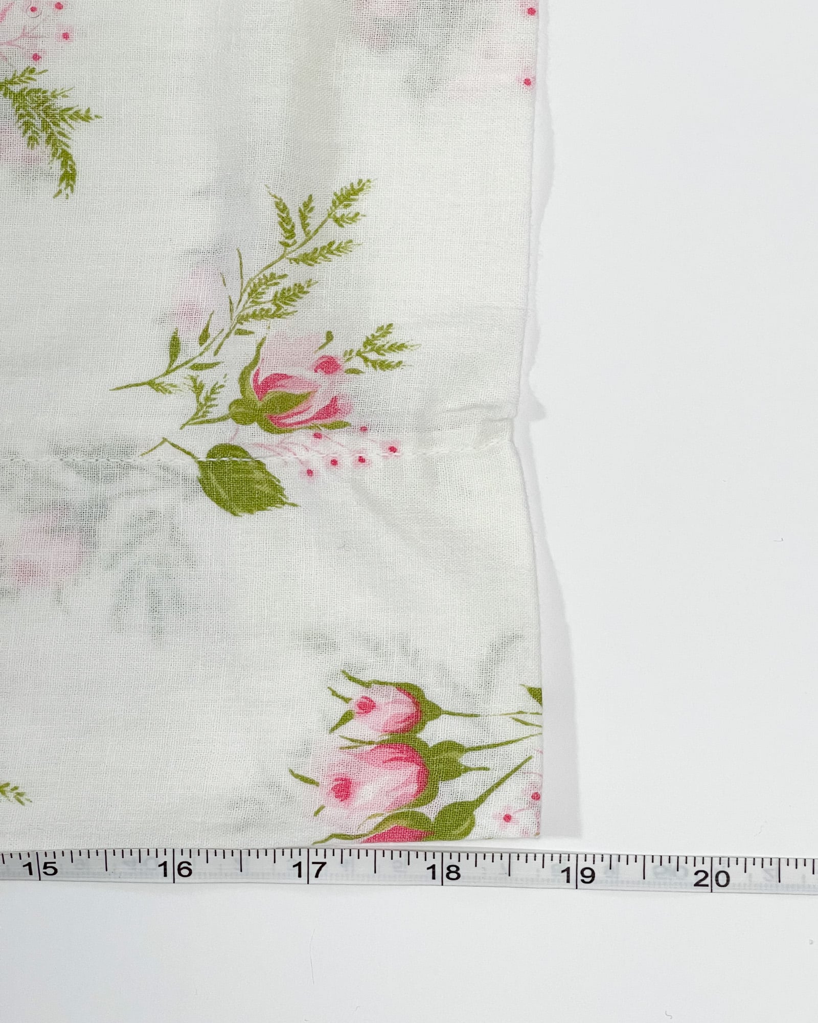 Vintage pink rose floral pillowcase shown with measuring tape indicating 19 inch width