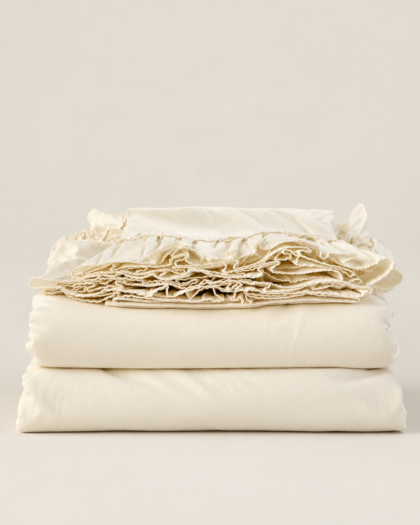 Off-white Ralph Lauren Bellosguardo king sheet set folded in a stack, with ruffled edges displayed on top.