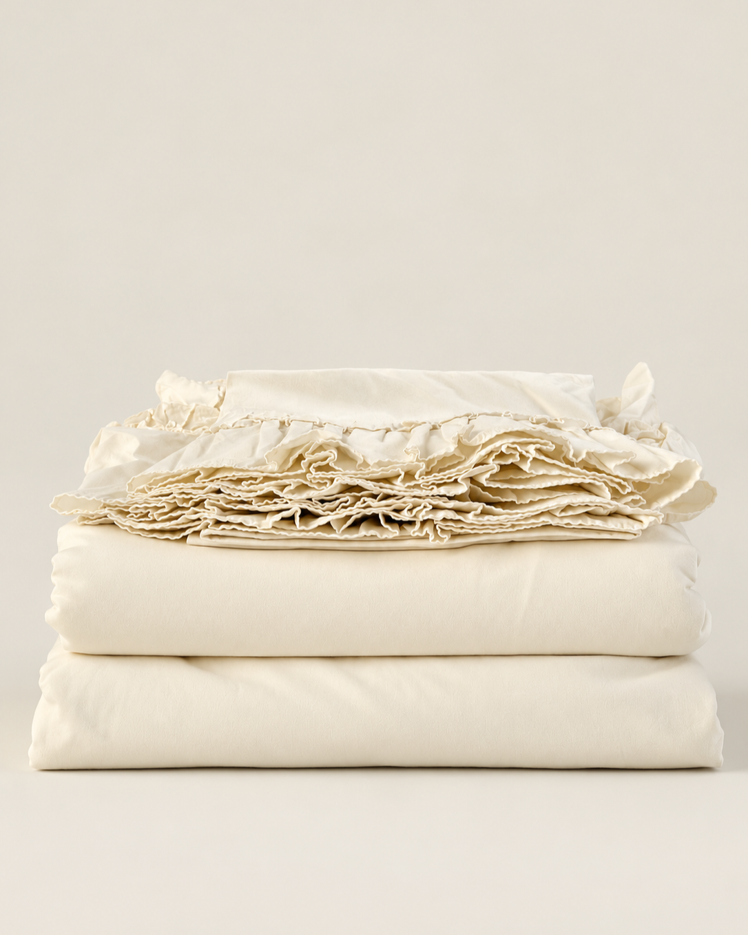 Off-white Ralph Lauren Bellosguardo king sheet set folded in a stack, with ruffled edges displayed on top.